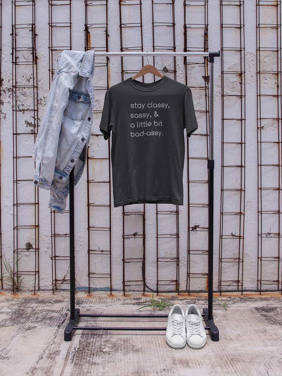 a grey kkpr tshirt hanging on a garment rack with a jean jacket and sneakers