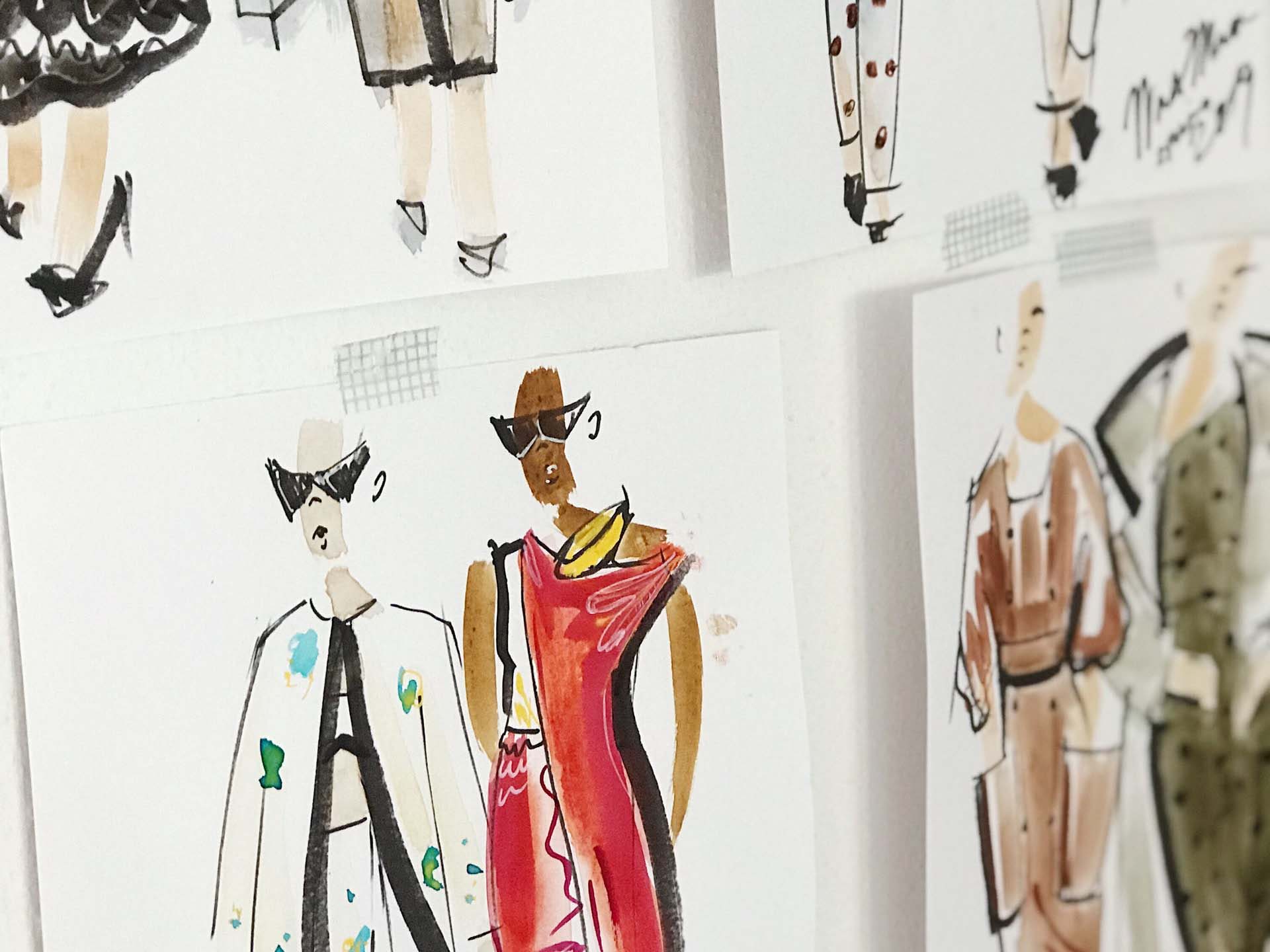 hand drawn fashion sketches taped up on a wall