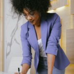 a black woman in business casual attire writing in a notebook